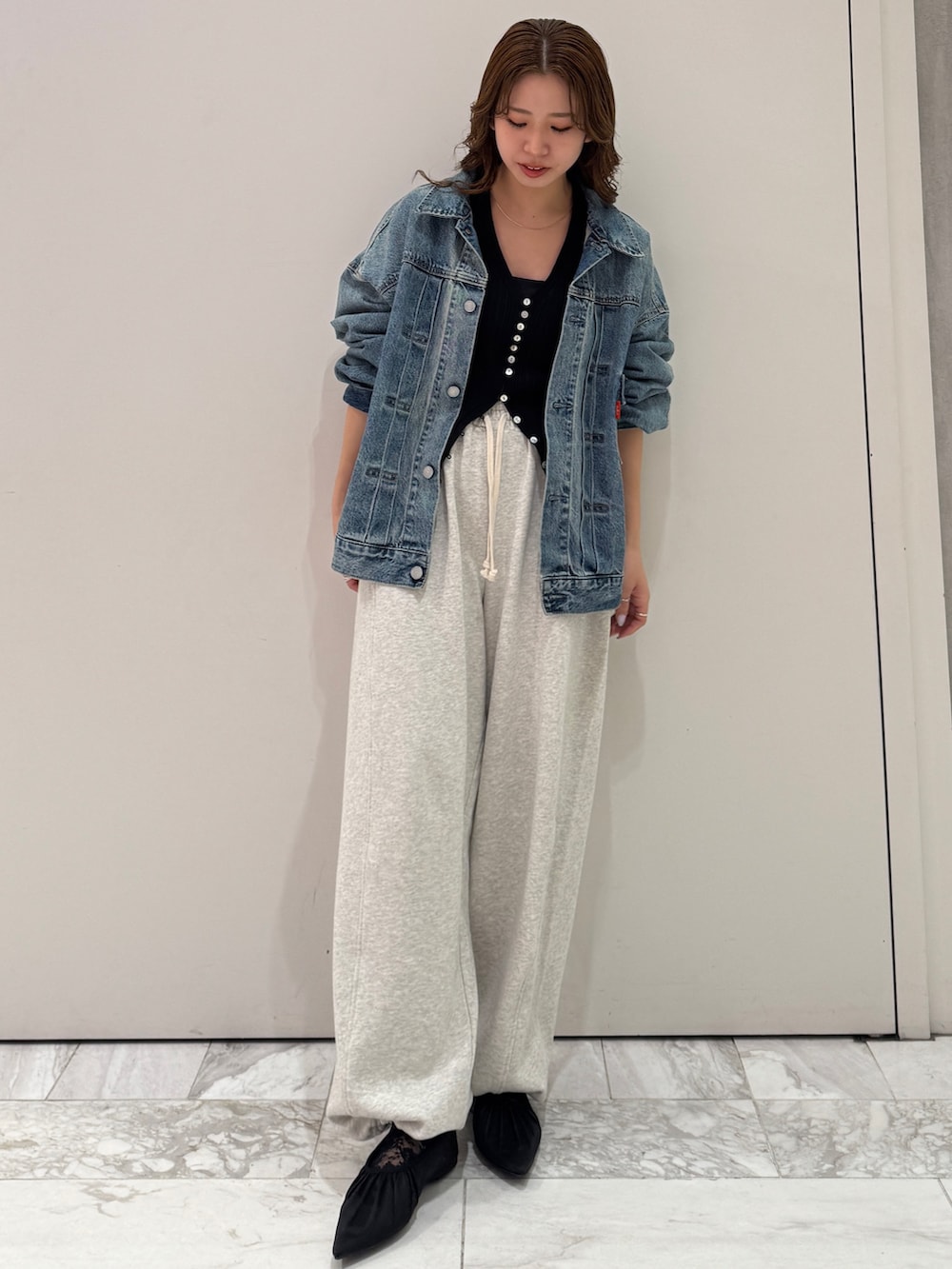 ブルー系のデニムジャケット、ブラック系のカーディガン/ボレロ、ホワイト系のスウェットパンツを着用したレディースの冬コーディネートの2枚目の写真