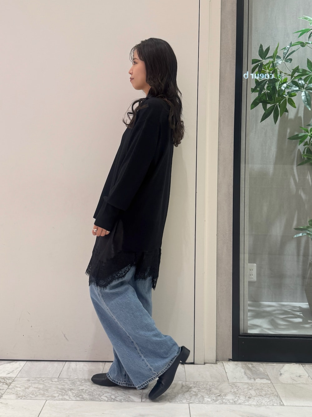ブラック系のニット/セーター、ブラック系のワンピース、ブルー系のデニムパンツを着用したレディースの秋コーディネートの2枚目の写真