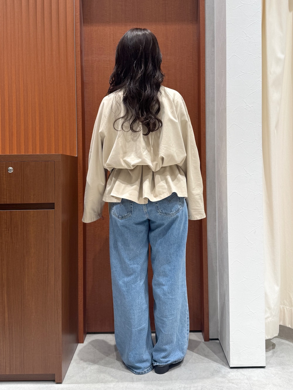 ベージュ系のトレンチコート、ブルー系のデニムパンツ、ブラック系のサンダルを着用したレディースの秋コーディネートの3枚目の写真