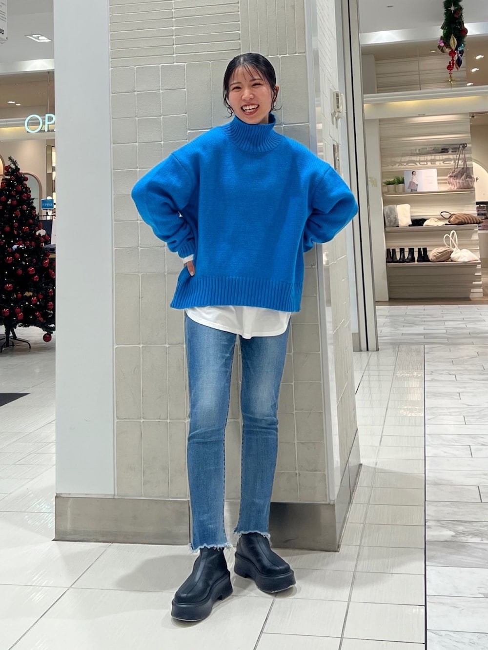 ブルー系のニット/セーター、ホワイト系のTシャツ/カットソー、ブラック系のブーツを着用したレディースの秋コーディネートの6枚目の写真