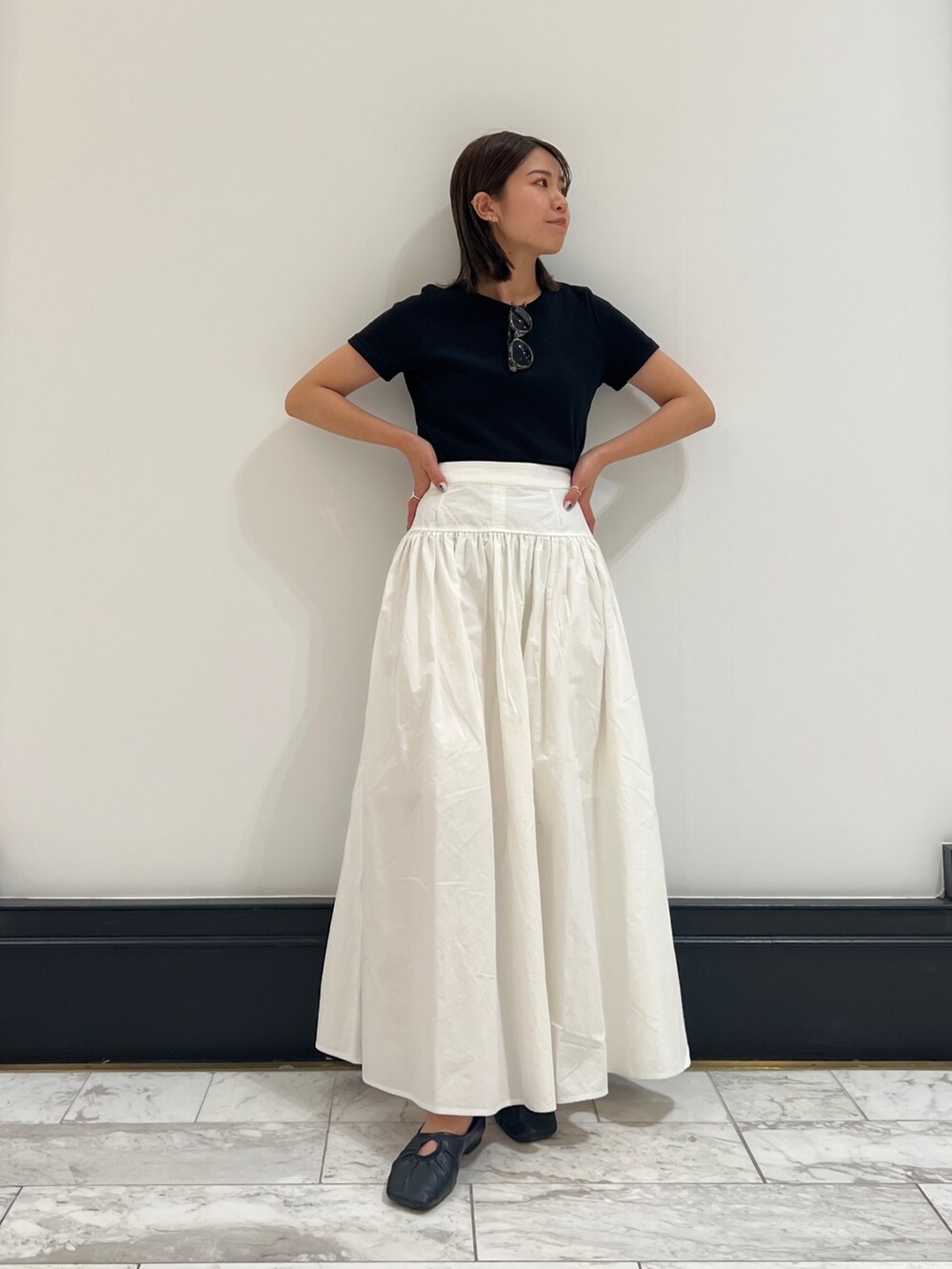 ホワイト系のスカート、ブラック系のTシャツ/カットソー、ブラック系のパンプスを着用したレディースの春コーディネートの4枚目の写真