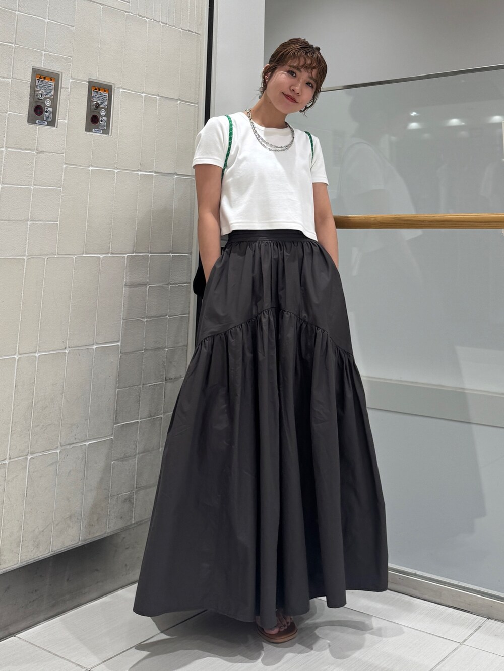 グレー系のスカート、シルバー系のサンダル、ホワイト系のTシャツ/カットソーを着用したレディースの春コーディネートの2枚目の写真