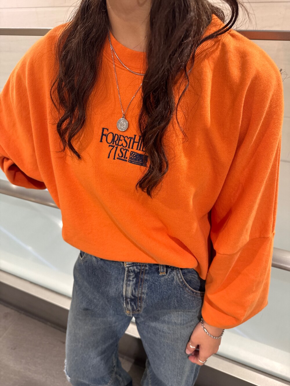 ブルー系のデニムパンツ、オレンジ系のスウェットを着用したレディースの冬コーディネートの6枚目の写真