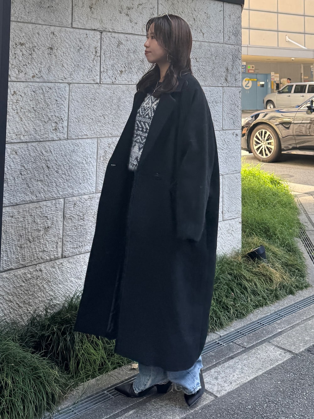 ブルー系のデニムパンツ、ブルー系のニット/セーター、ブラック系のチェスターコートを着用したレディースの秋コーディネートの5枚目の写真