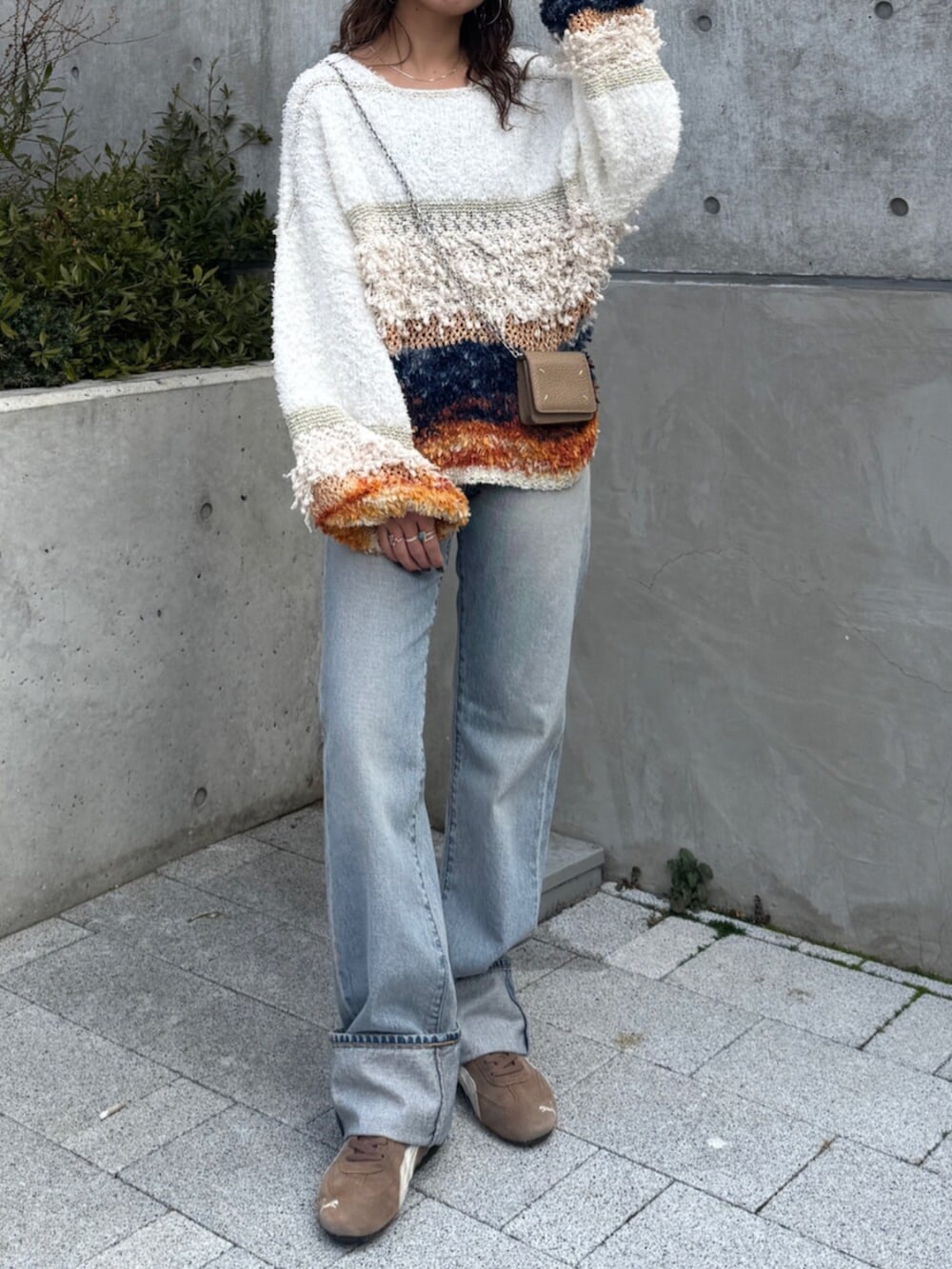 ブルー系のデニムパンツ、ホワイト系のニット/セーター、ブラウン系のスニーカーを着用したレディースの冬コーディネートの2枚目の写真