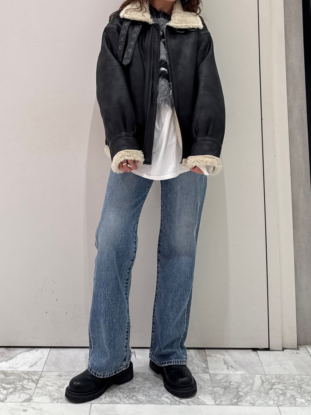 ブラック系のニット/セーター、ホワイト系のTシャツ/カットソー、ブラック系のブーツを着用したレディースの冬コーディネートの2枚目の写真