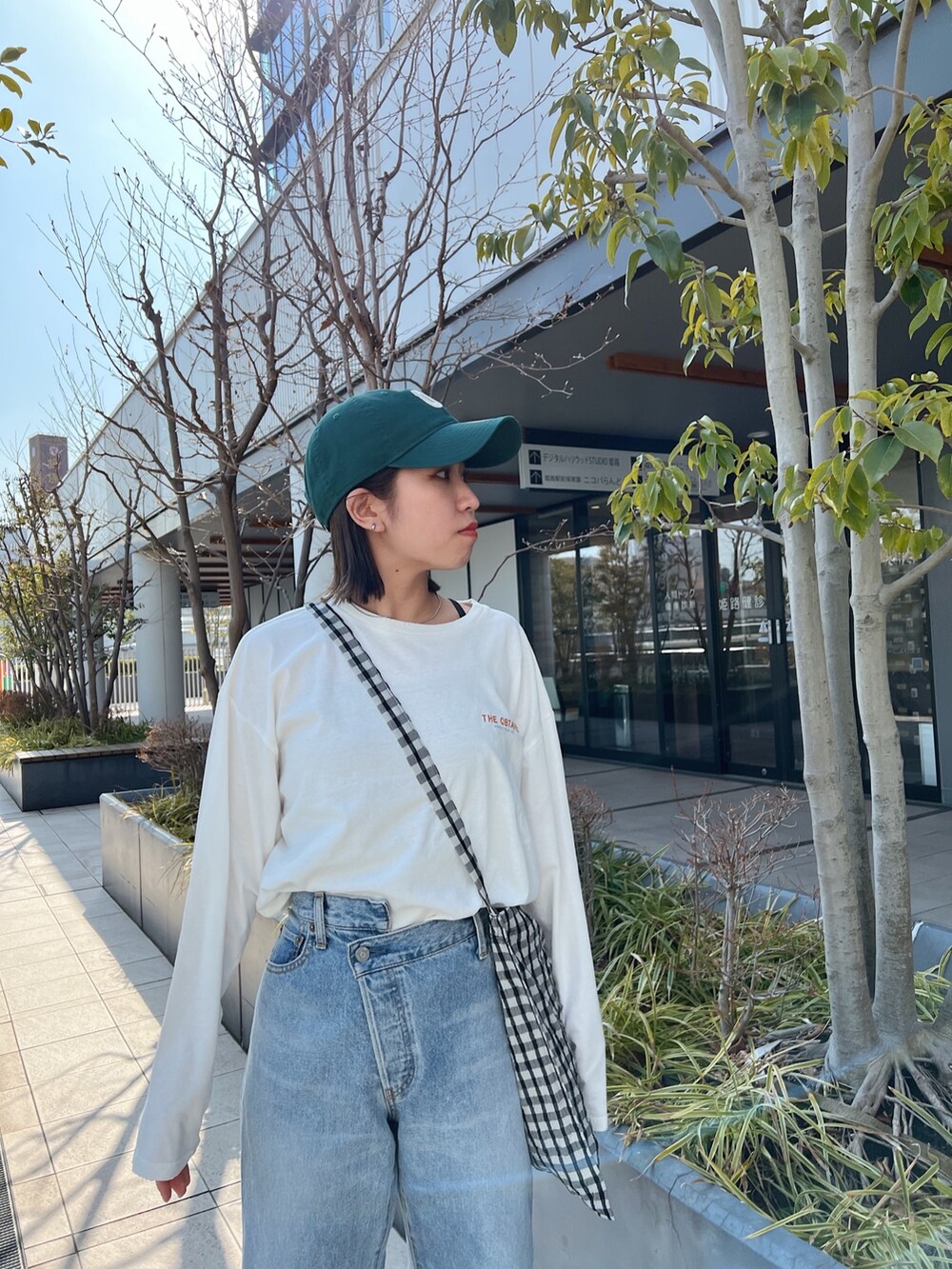 ブルー系のデニムパンツ、ホワイト系のTシャツ/カットソー、グレー系のショルダーバッグを着用したレディースの冬コーディネートの6枚目の写真