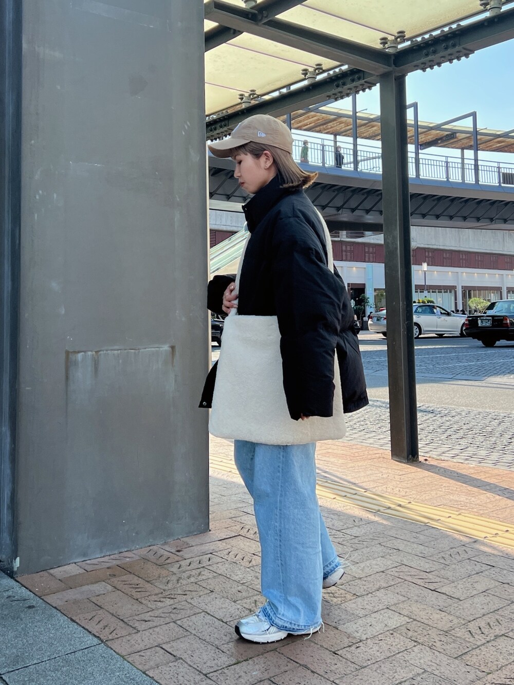 ブラック系のダウンジャケット/コート、ホワイト系のショルダーバッグ、ブルー系のデニムパンツを着用したレディースの秋コーディネートの4枚目の写真