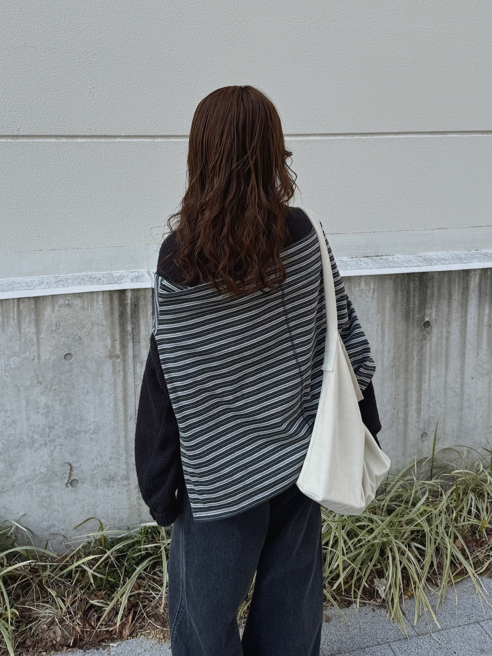 グレー系のニット/セーター、グレー系のTシャツ/カットソー、ブラック系のデニムパンツを着用したレディースの冬コーディネートの9枚目の写真