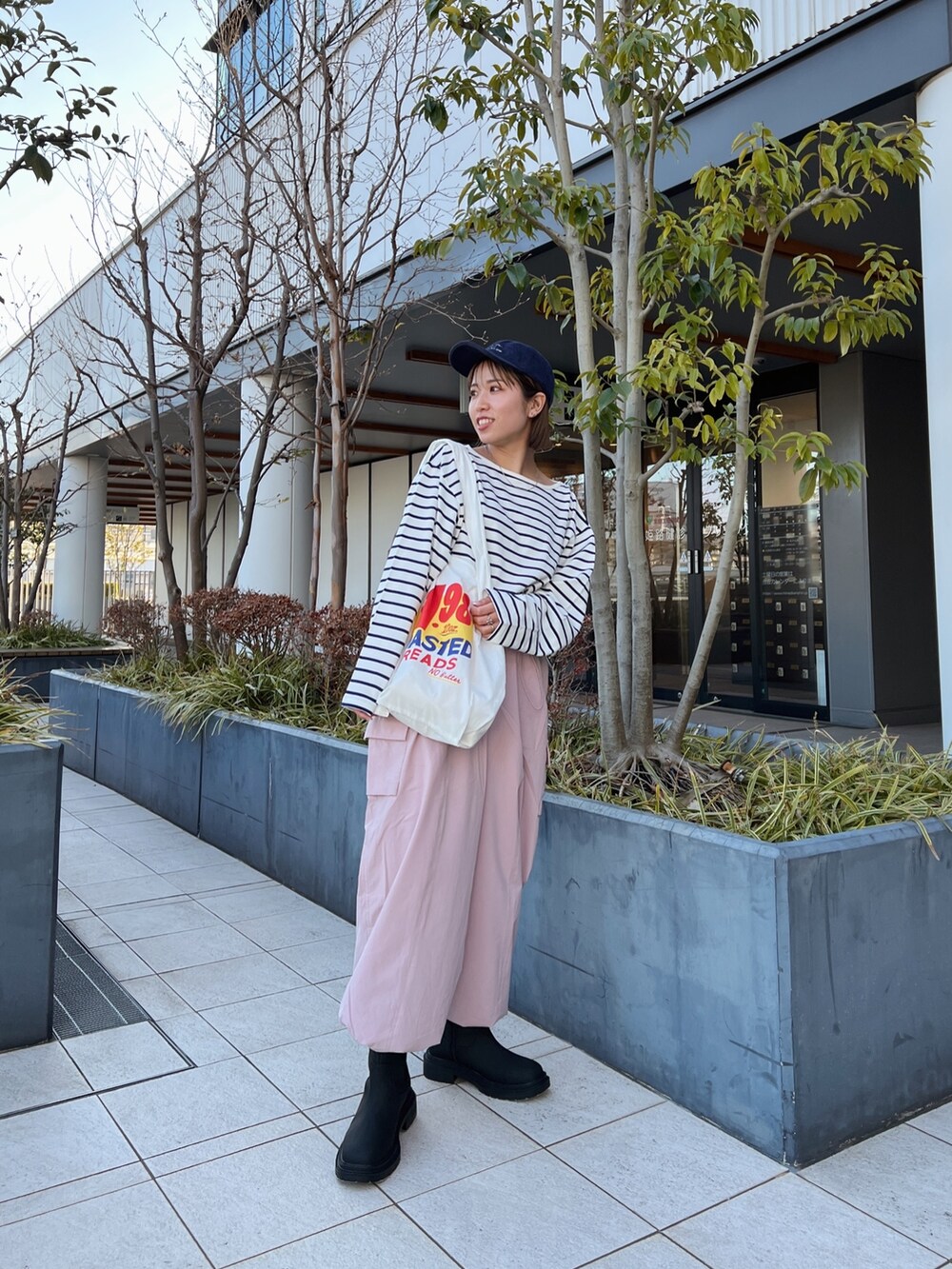 ピンク系のカーゴパンツ、ホワイト系のエコバッグ/サブバッグ、ブルー系のTシャツ/カットソーを着用したレディースの冬コーディネートの4枚目の写真