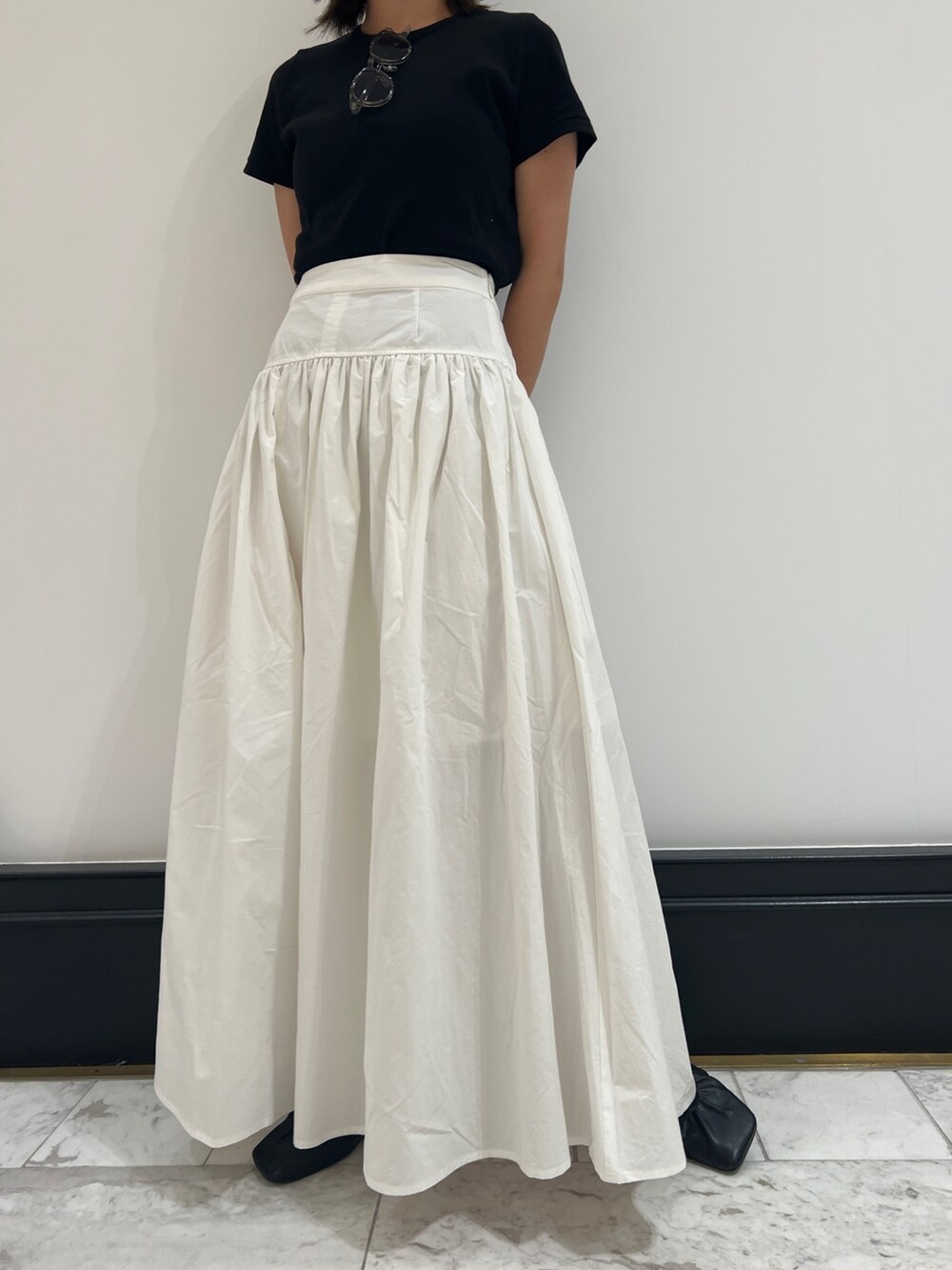 ホワイト系のスカート、ブラック系のTシャツ/カットソー、ブラック系のパンプスを着用したレディースの春コーディネートの9枚目の写真