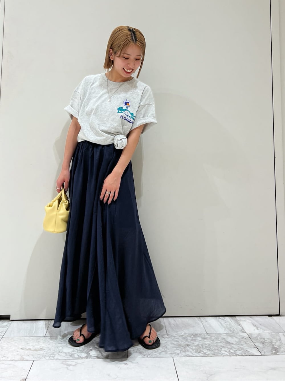 ブラック系のサンダル、ブルー系のスカート、イエロー系のハンドバッグを着用したレディースの春コーディネートの4枚目の写真