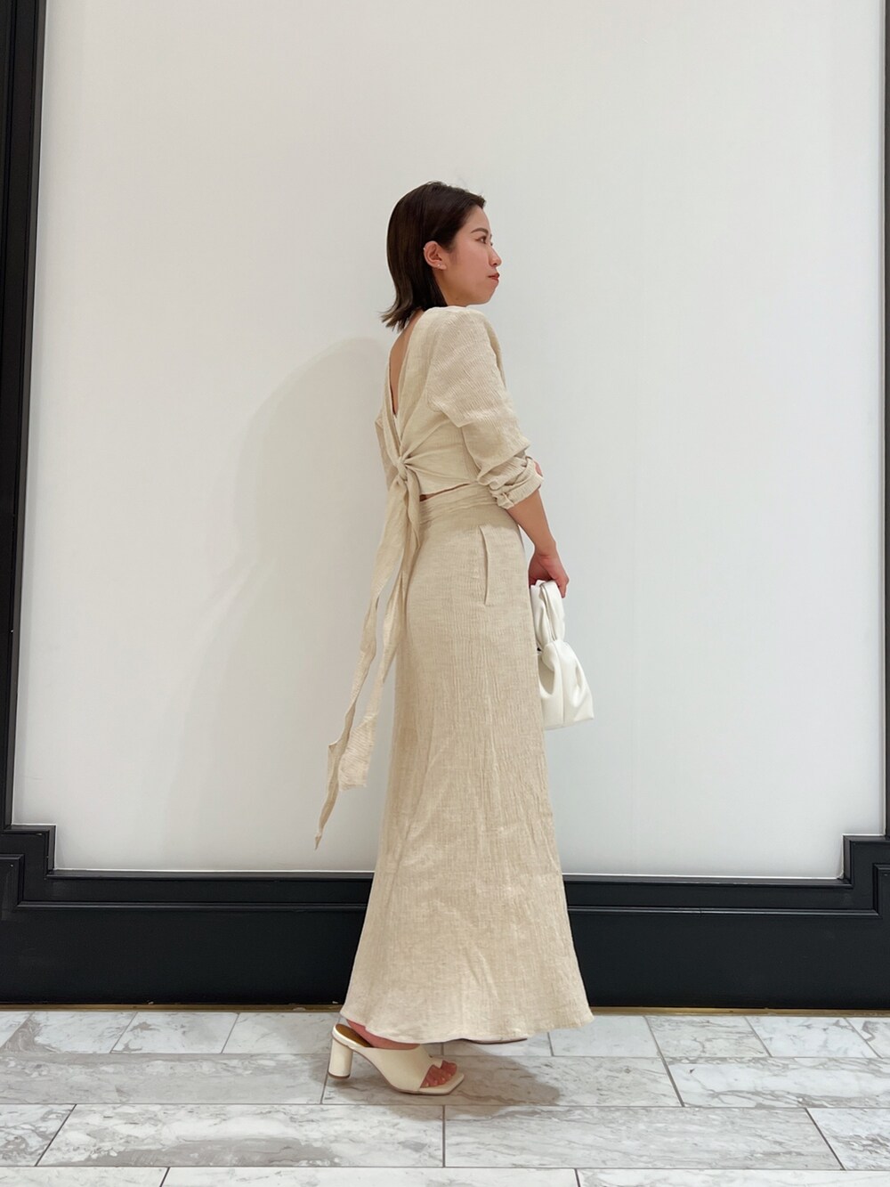 ホワイト系のベスト、ホワイト系のワンピース、ホワイト系のハンドバッグを着用したレディースの春コーディネートの2枚目の写真