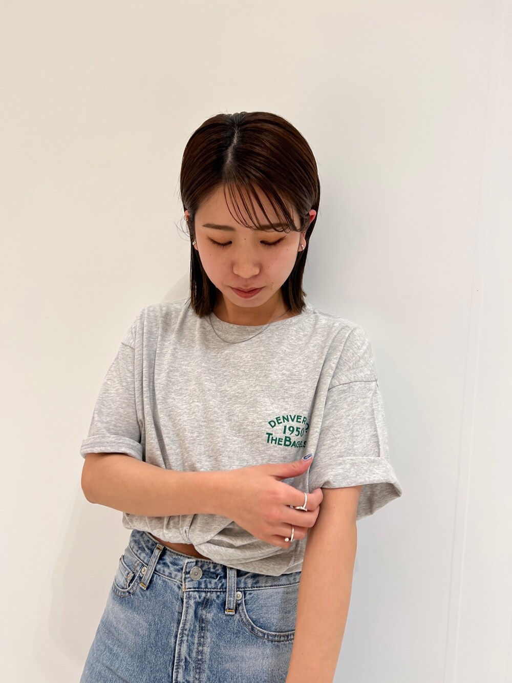 ブルー系のデニムパンツ、グレー系のTシャツ/カットソー、ホワイト系のスニーカーを着用したレディースの春コーディネートの4枚目の写真