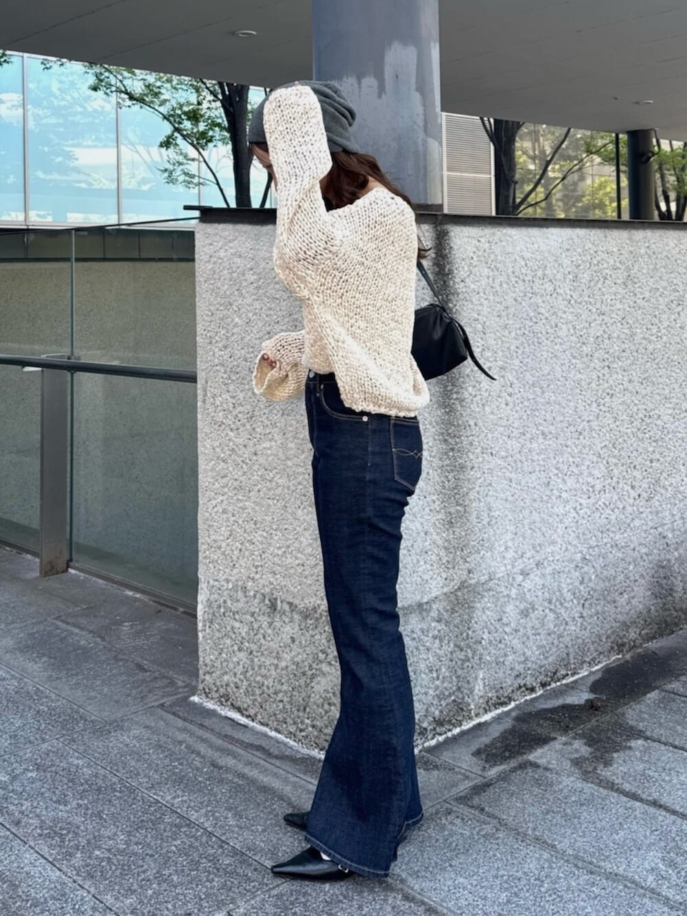 ブラック系のハンドバッグ、ブルー系のデニムパンツ、ブラック系のパンプスを着用したレディースの秋コーディネートの4枚目の写真
