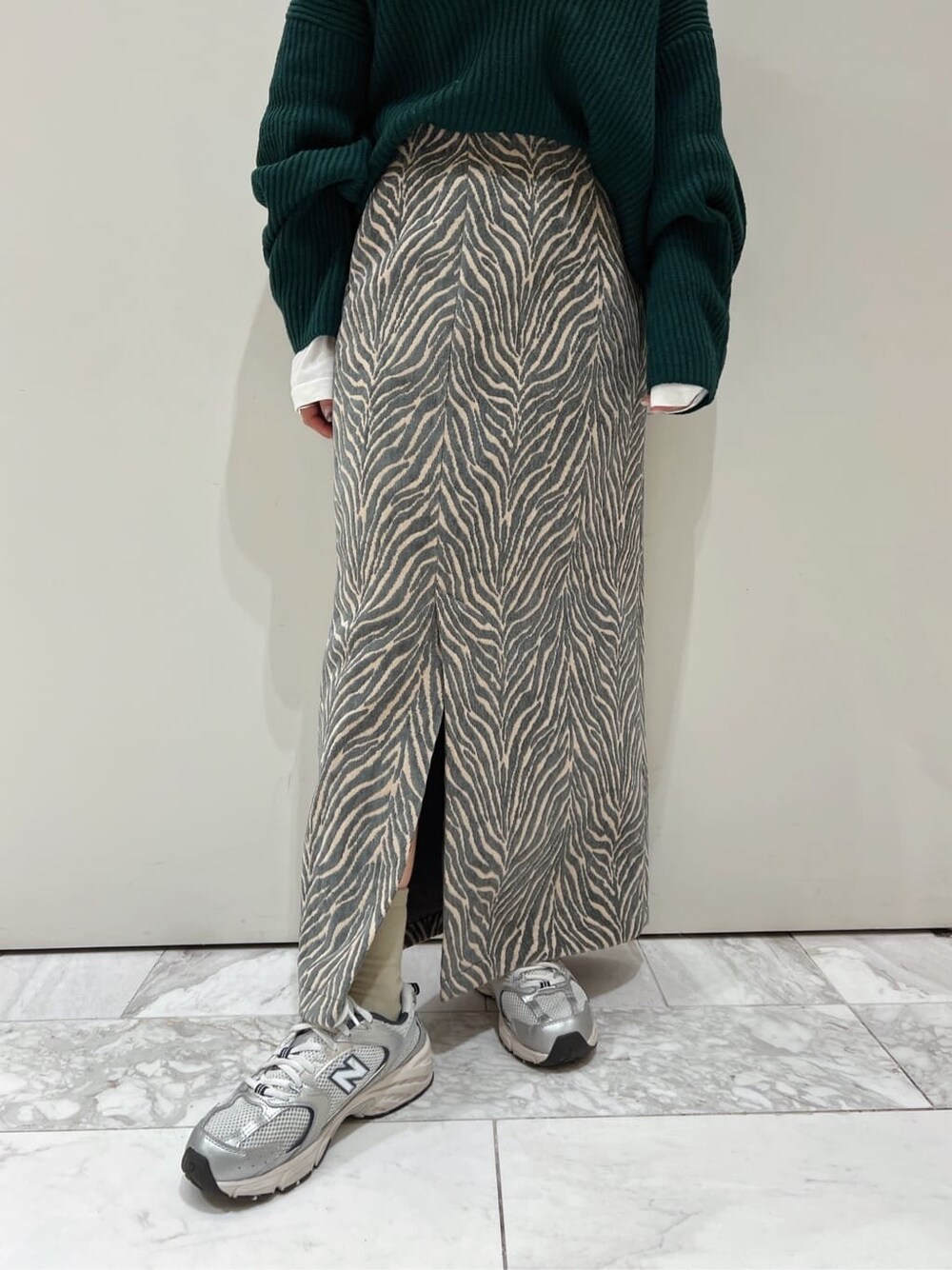 ホワイト系のTシャツ/カットソー、ブルー系のスカート、グリーン系のニット/セーターを着用したレディースの秋コーディネートの7枚目の写真