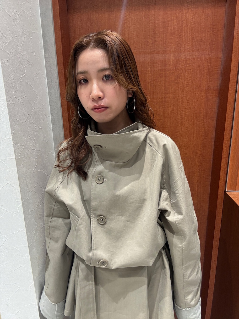 グリーン系のトレンチコート、ブルー系のデニムパンツ、ブラック系のブーツを着用したレディースの冬コーディネートの6枚目の写真