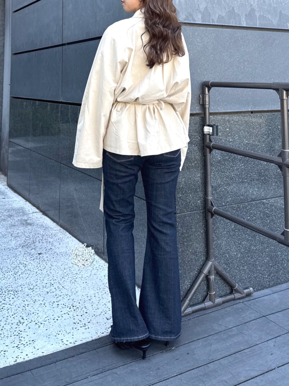 ベージュ系のトレンチコート、ブルー系のデニムパンツ、ブラック系のパンプスを着用したレディースの秋コーディネートの5枚目の写真