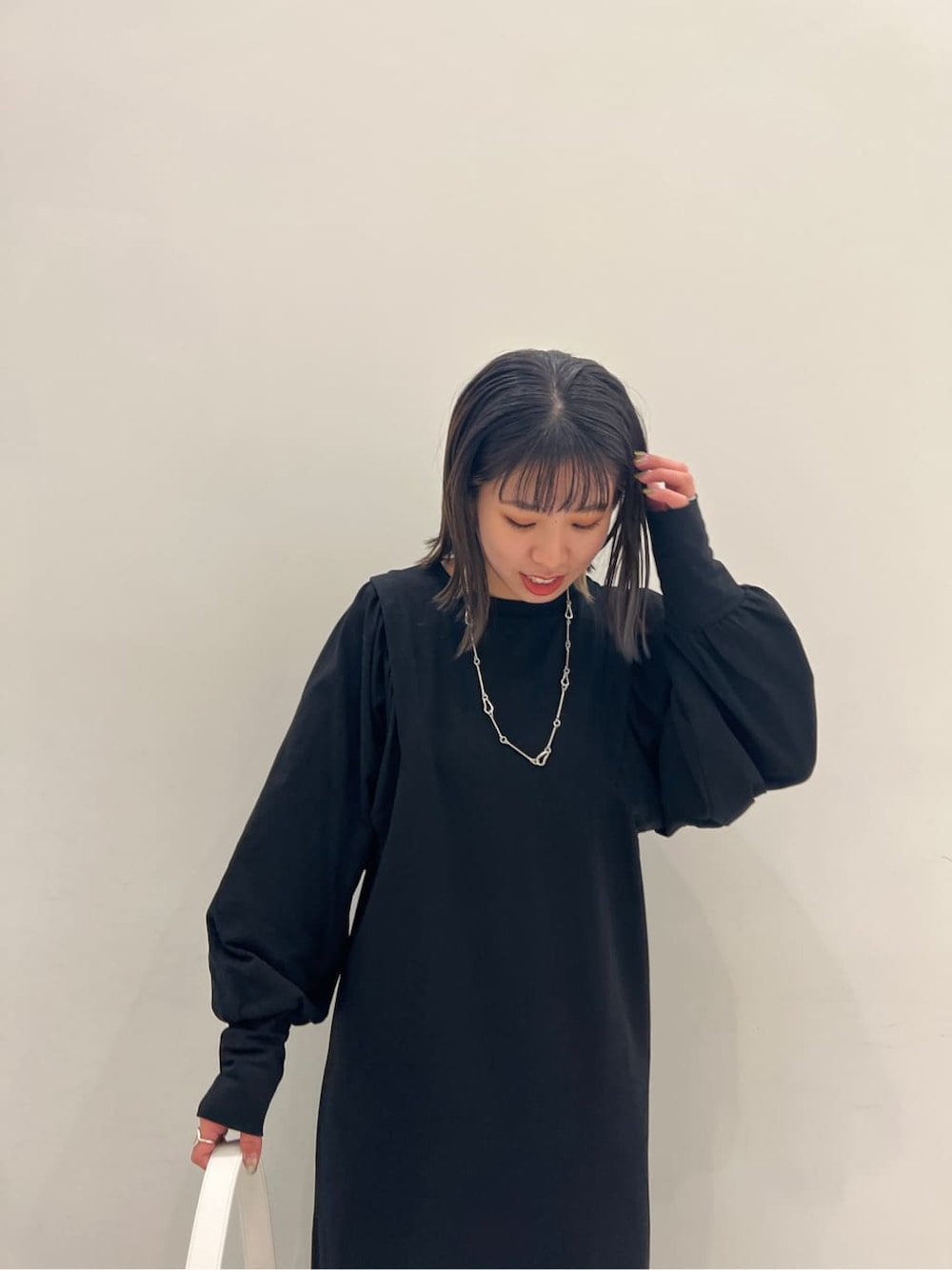 ブラック系のワンピース、ブラック系のブーツ、ホワイト系のハンドバッグを着用したレディースの冬コーディネートの2枚目の写真