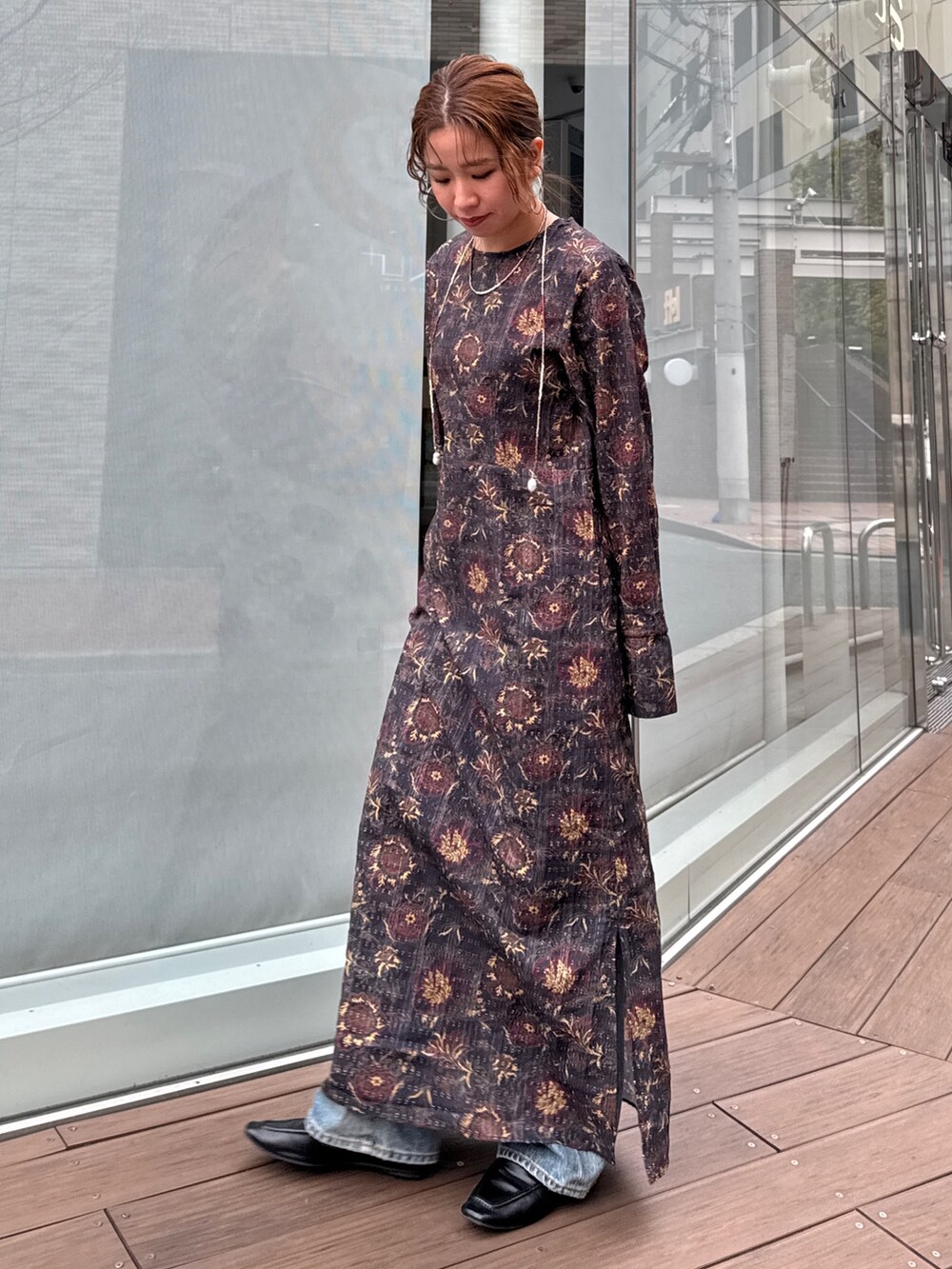 ブラック系のワンピース、ブルー系のデニムパンツ、ブラウン系のネックレスを着用したレディースの冬コーディネートの5枚目の写真