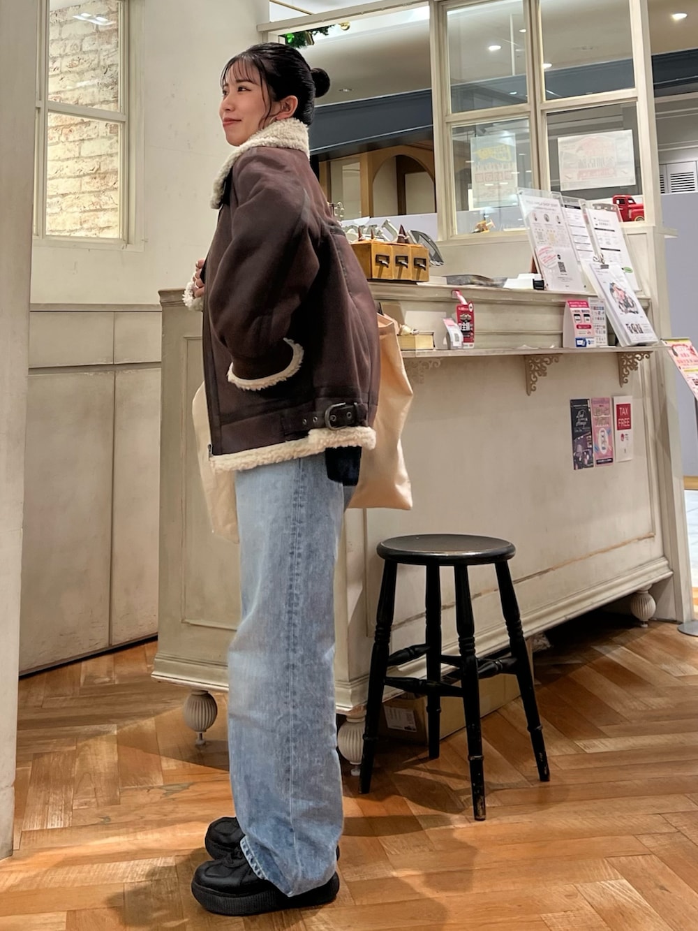 オレンジ系のニット/セーター、ホワイト系のTシャツ/カットソー、ブルー系のデニムパンツを着用したレディースの冬コーディネートの2枚目の写真