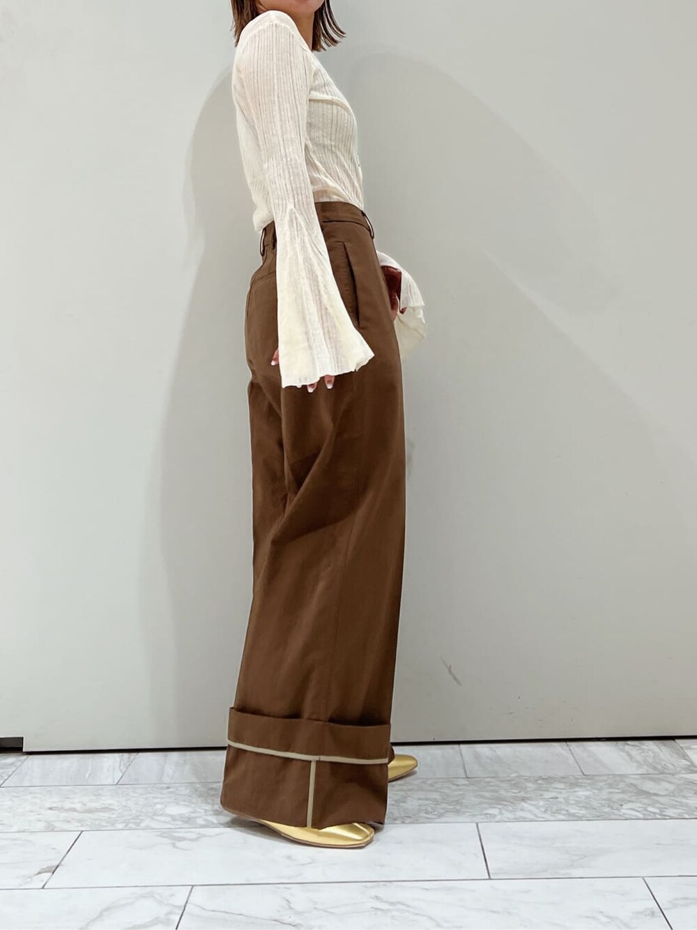 ブラウン系のチノパンツ、ゴールド系のパンプス、ホワイト系のカーディガン/ボレロを着用したレディースの夏コーディネートの4枚目の写真