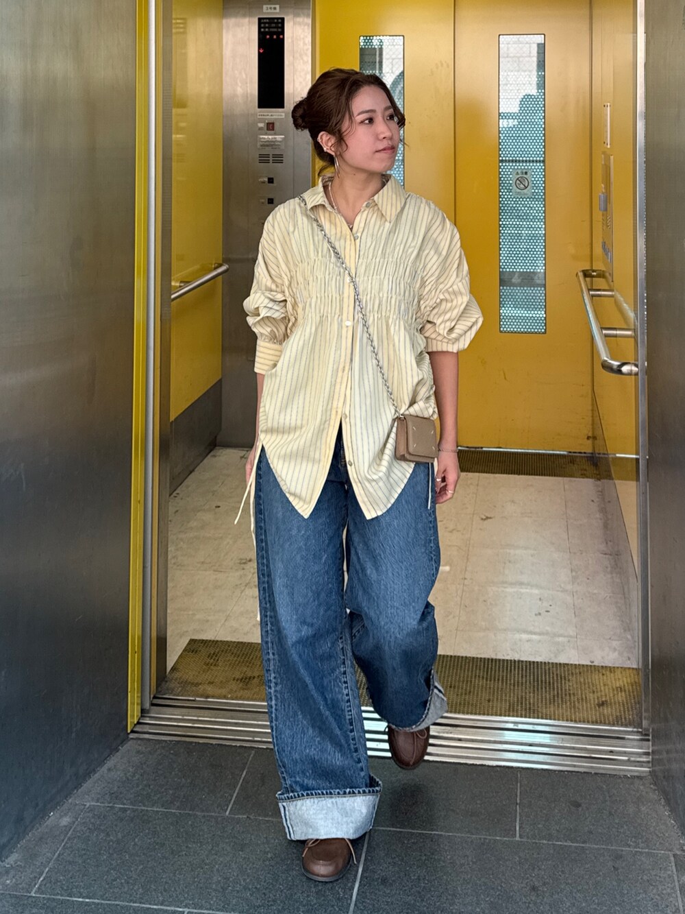 イエロー系のシャツ/ブラウス、ブルー系のデニムパンツ、ブラウン系のローファーを着用したレディースの冬コーディネートの9枚目の写真