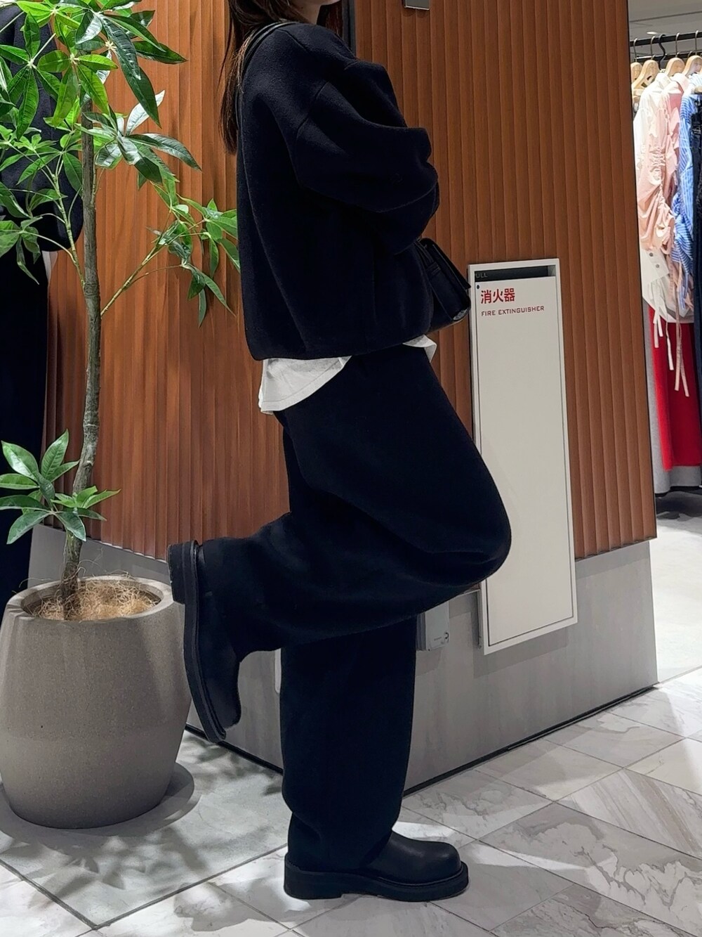ブラック系のニット/セーター、ブラック系のブーツ、ブラック系のハンドバッグを着用したレディースの冬コーディネートの5枚目の写真