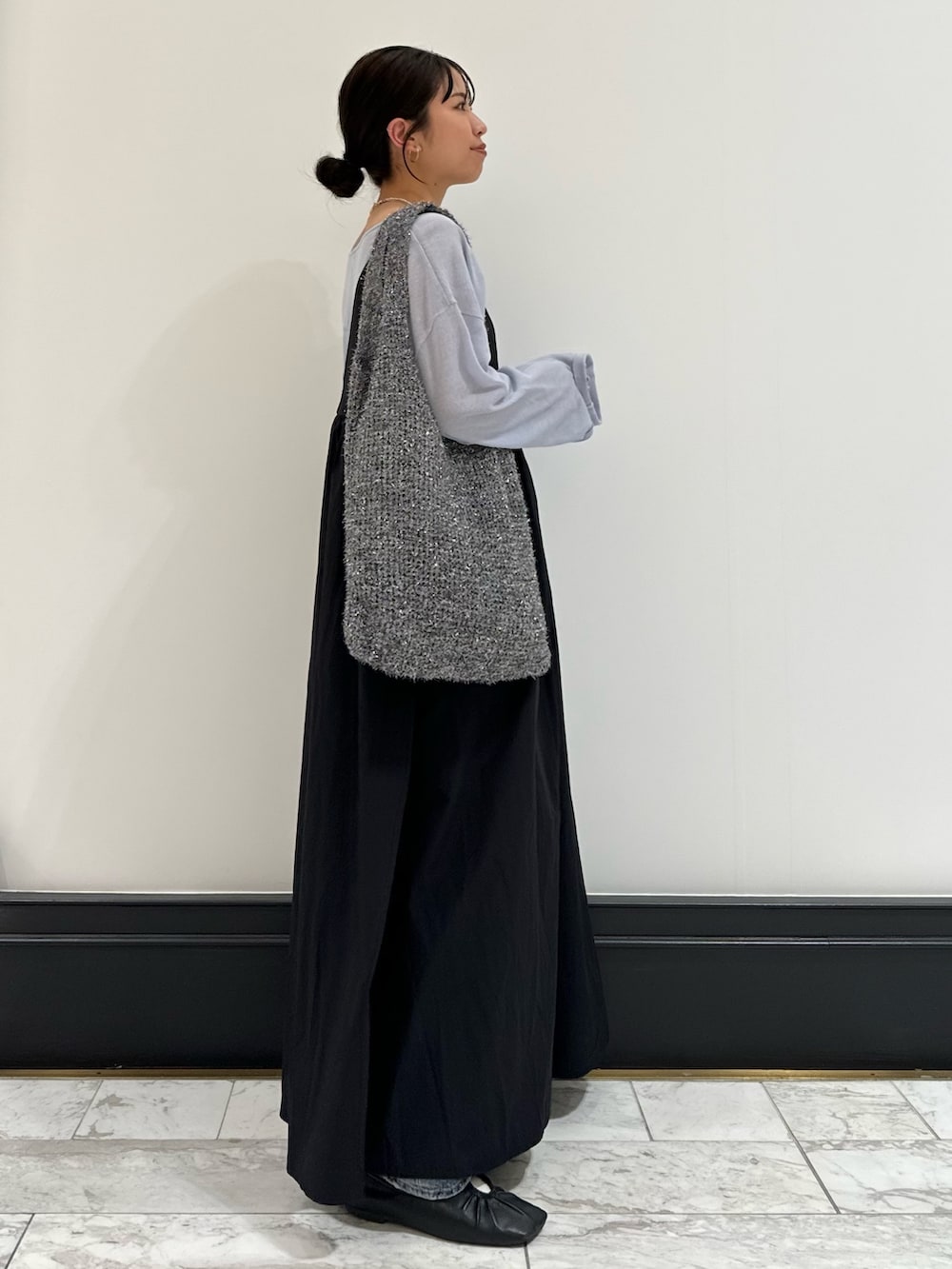 ブラック系のワンピース、ブルー系のニット/セーター、ブルー系のデニムパンツを着用したレディースの春コーディネートの2枚目の写真