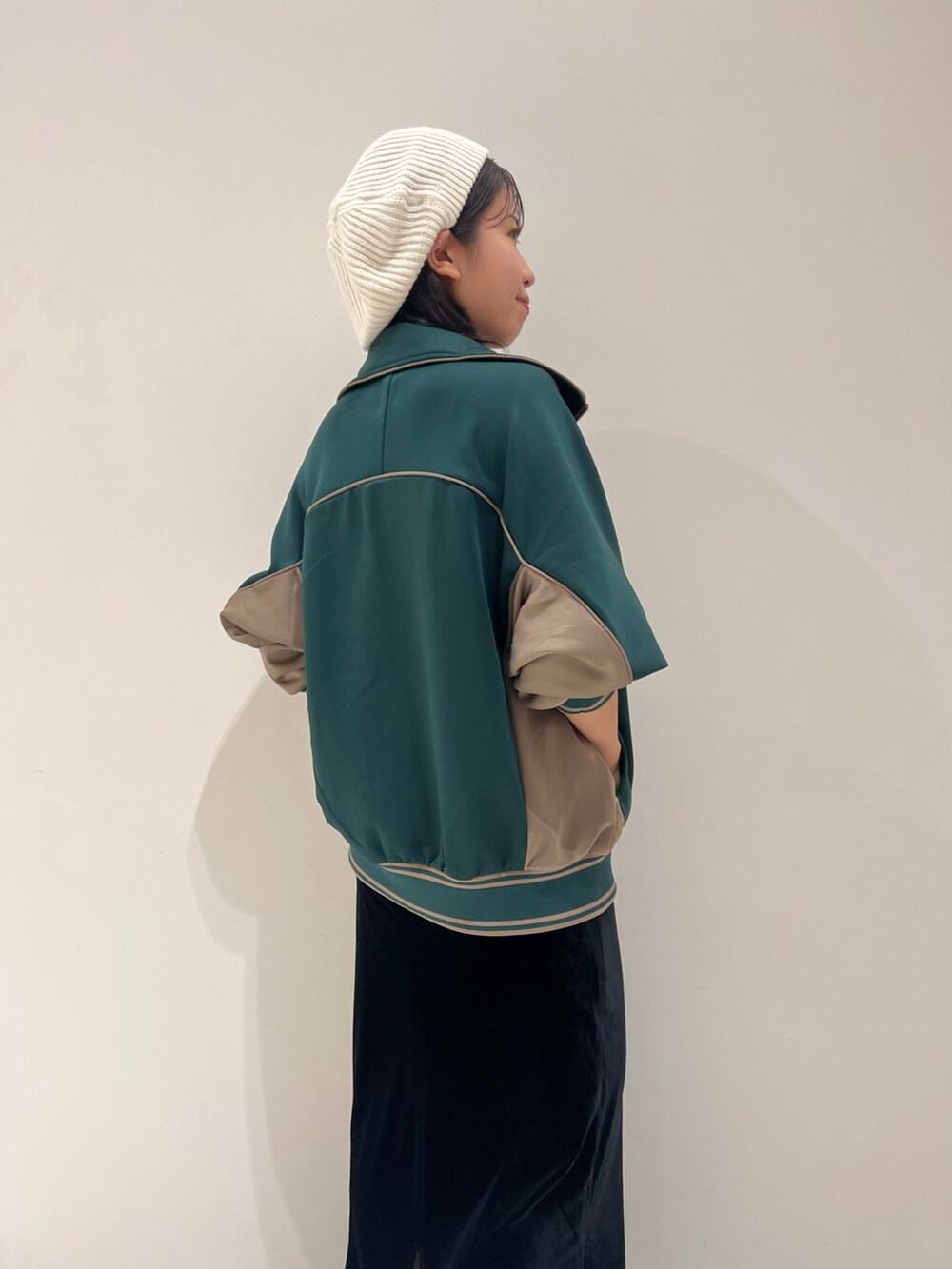 ブラック系のスカート、グリーン系のブルゾン、ホワイト系のキャミソールを着用したレディースの秋コーディネートの5枚目の写真