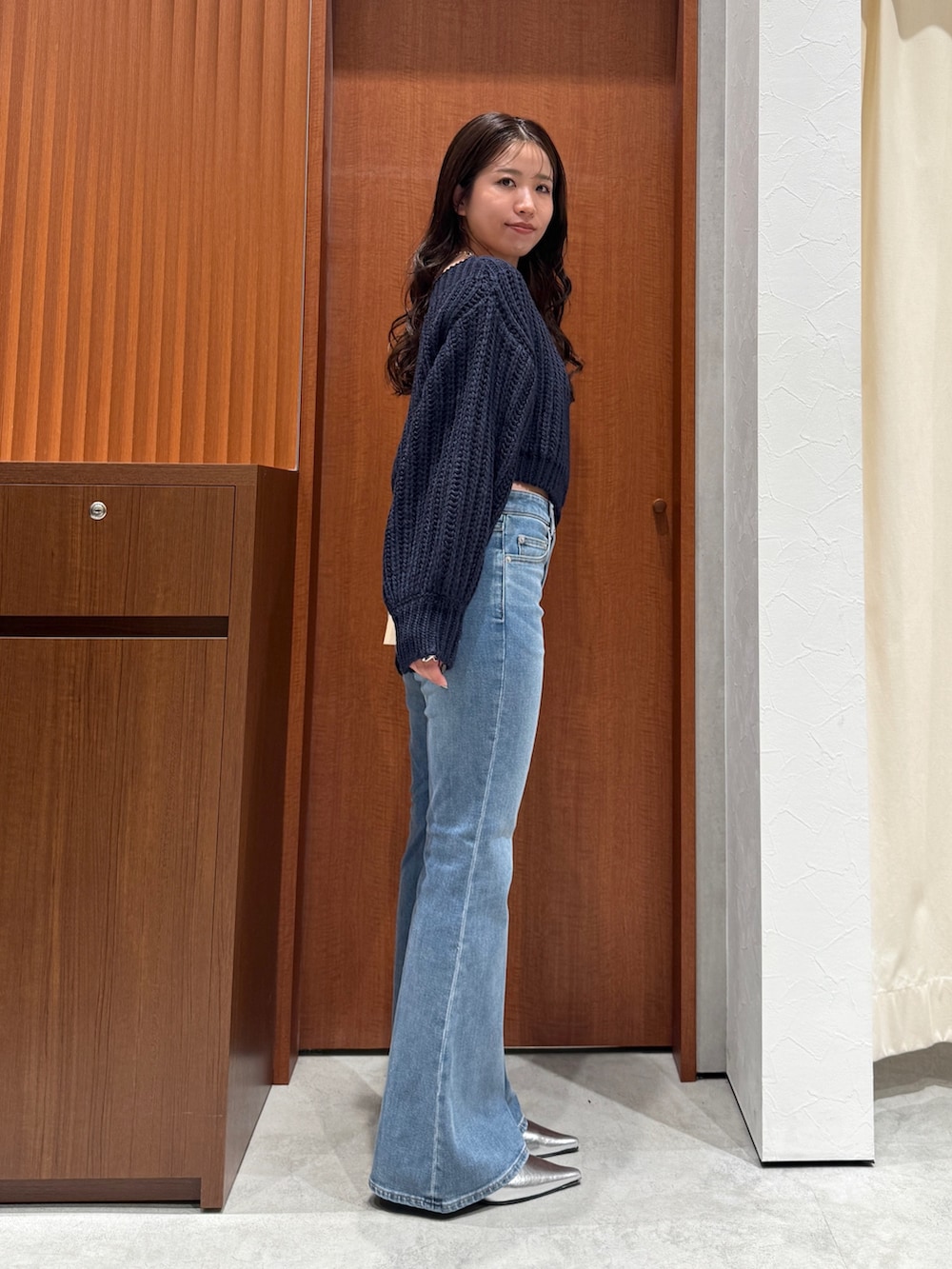 ブルー系のニット/セーター、ブルー系のデニムパンツ、シルバー系のパンプスを着用したレディースの秋コーディネートの3枚目の写真