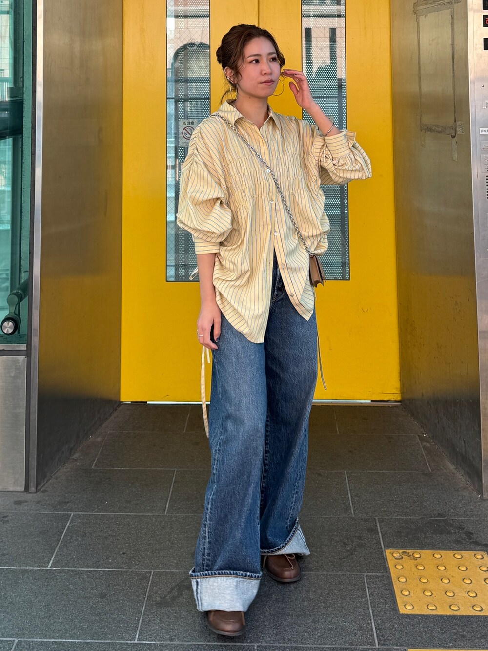 イエロー系のシャツ/ブラウス、ブルー系のデニムパンツ、ブラウン系のローファーを着用したレディースの冬コーディネートの2枚目の写真