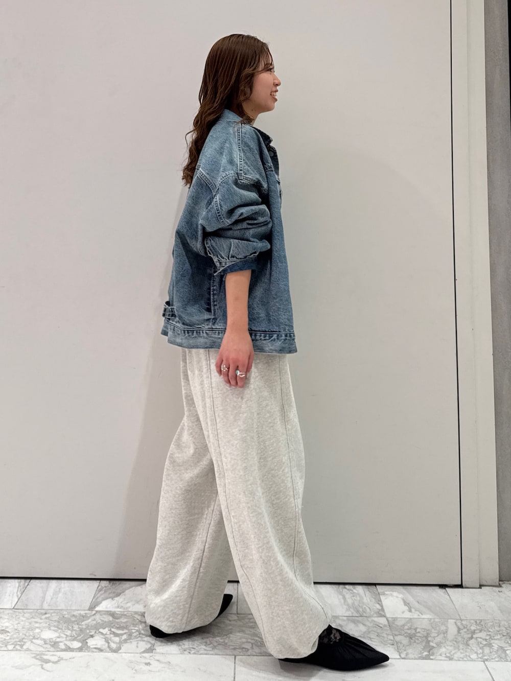 ブルー系のデニムジャケット、ブラック系のカーディガン/ボレロ、ホワイト系のスウェットパンツを着用したレディースの冬コーディネートの3枚目の写真