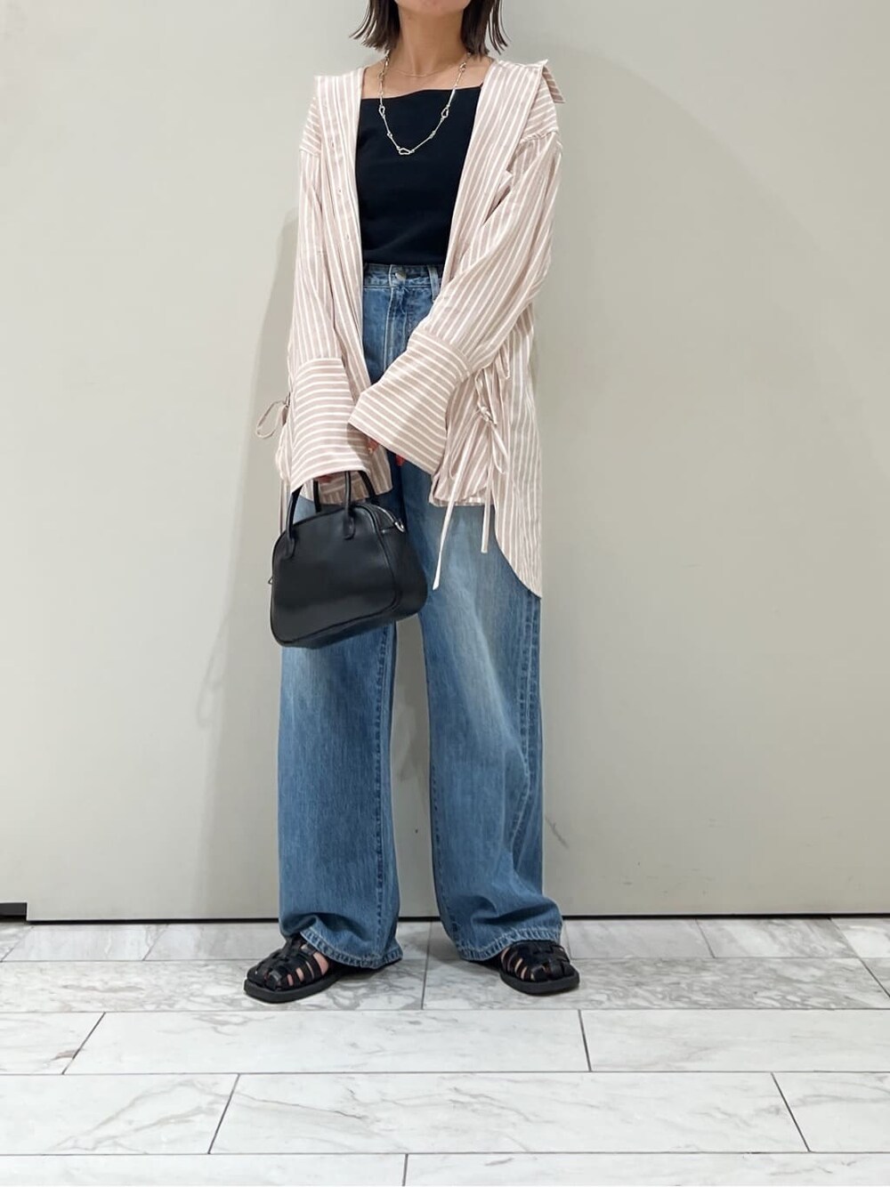 ブラック系のサンダル、ピンク系のシャツ/ブラウス、ブラック系のハンドバッグを着用したレディースの春コーディネートの3枚目の写真