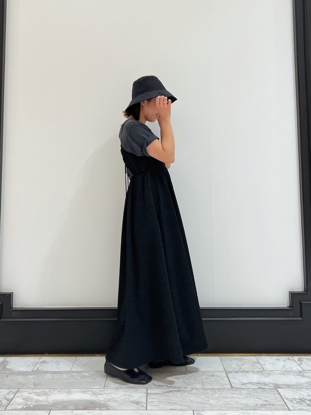 ブラック系のワンピース、グレー系のTシャツ/カットソー、ブラック系のパンプスを着用したレディースの春コーディネートの3枚目の写真