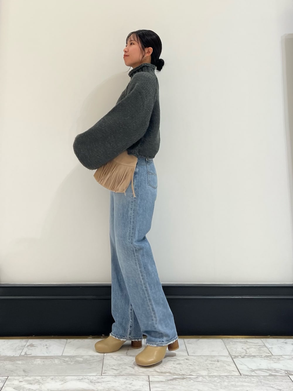 ブルー系のデニムパンツ、グレー系のニット/セーター、ベージュ系のブーツを着用したレディースの秋コーディネートの3枚目の写真