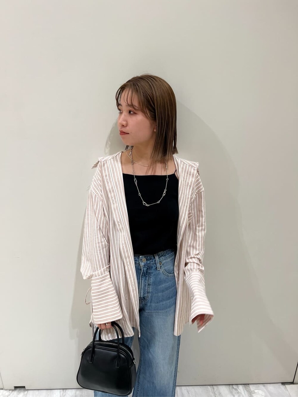 ブラック系のサンダル、ピンク系のシャツ/ブラウス、ブラック系のハンドバッグを着用したレディースの春コーディネートの7枚目の写真