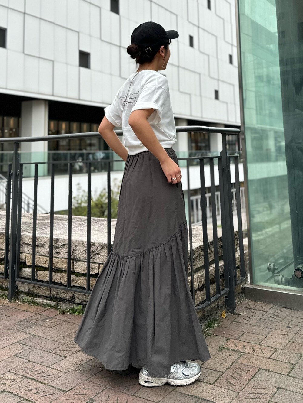 シルバー系のショルダーバッグ、ホワイト系のTシャツ/カットソー、グレー系のスカートを着用したレディースの春コーディネートの6枚目の写真