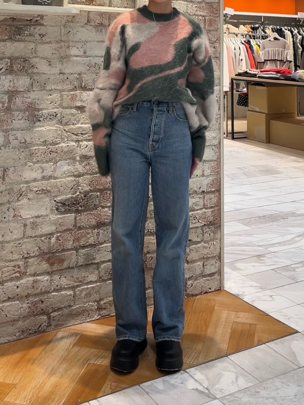 ブラック系のブーツ、グリーン系のニット/セーター、ブルー系のデニムパンツを着用したレディースの秋コーディネートの7枚目の写真