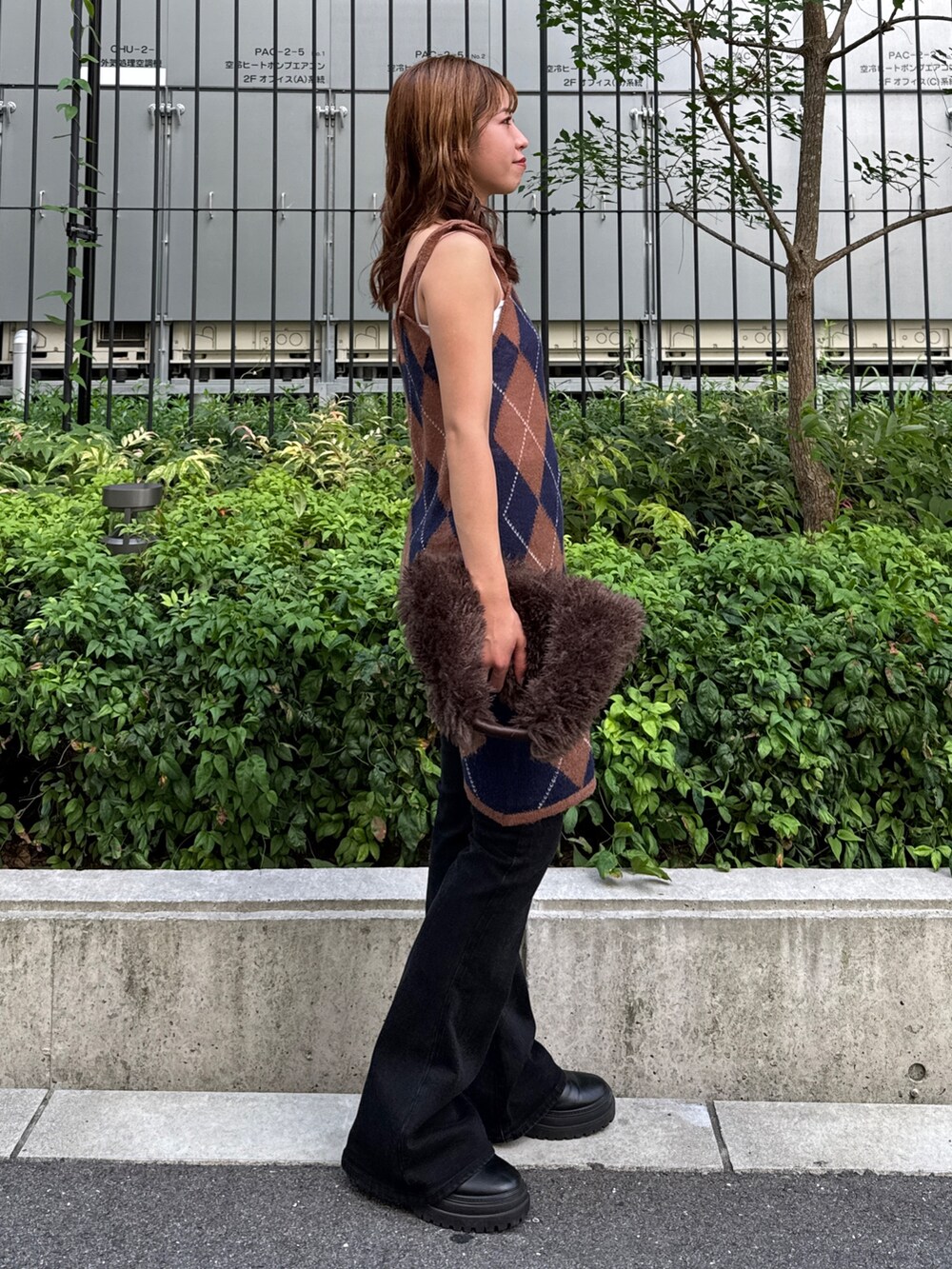 ブラウン系のニット/セーター、ブラック系のデニムパンツ、ブラウン系のハンドバッグを着用したレディースの夏コーディネートの5枚目の写真