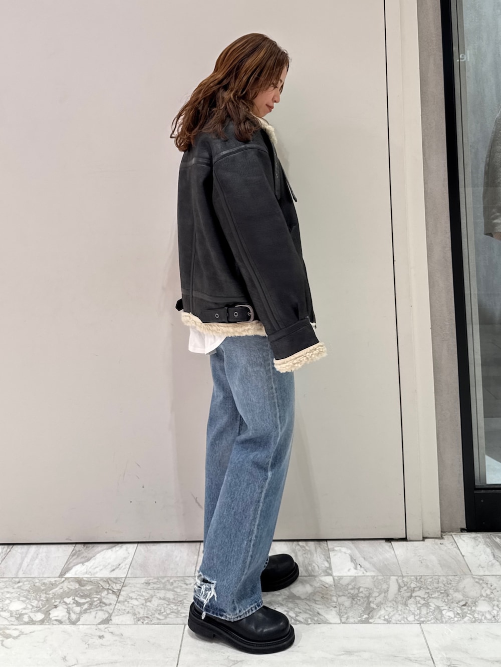 ブラック系のニット/セーター、ホワイト系のTシャツ/カットソー、ブラック系のブーツを着用したレディースの冬コーディネートの8枚目の写真