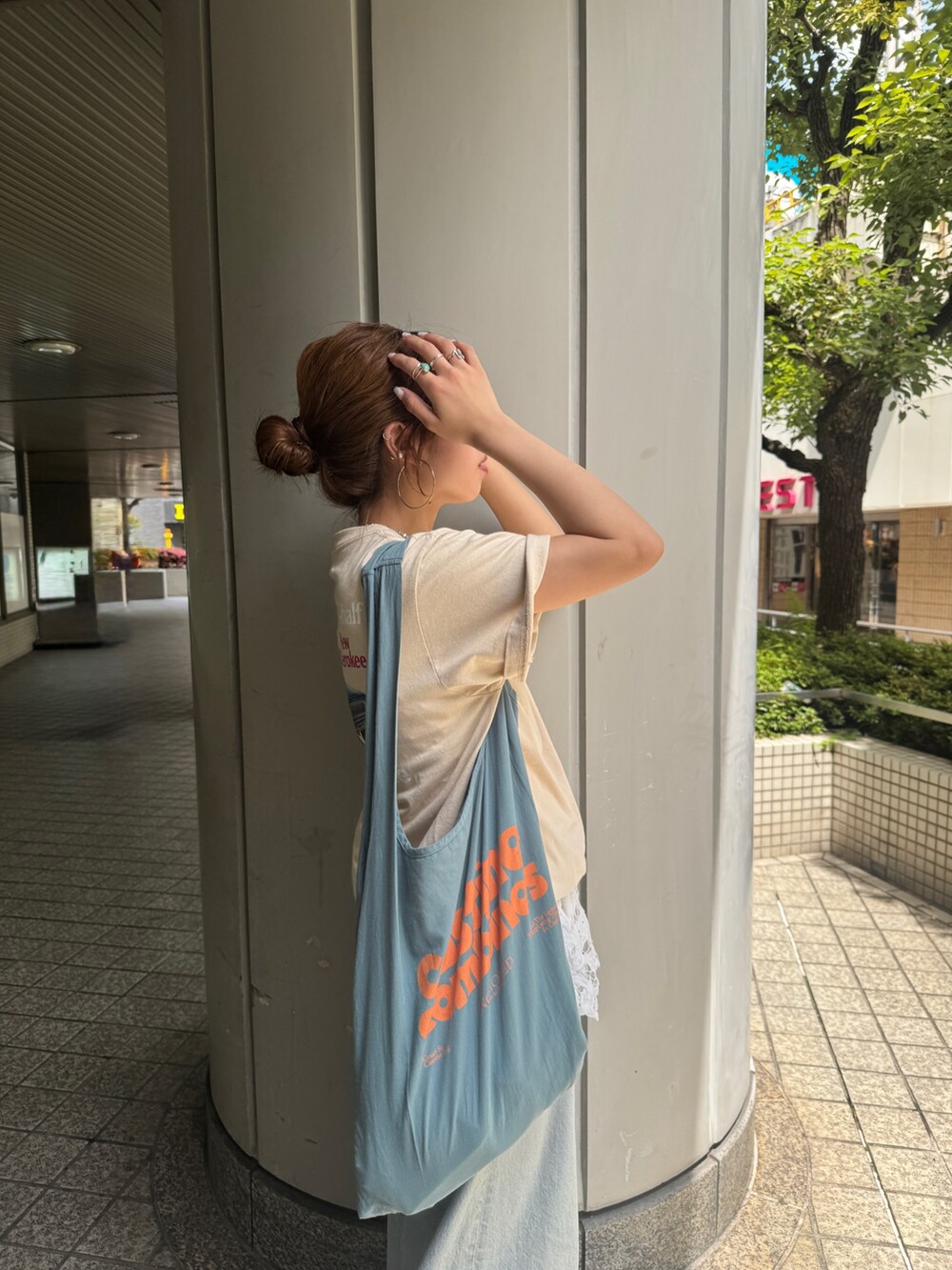 ブルー系のデニムパンツ、ブルー系のトートバッグ、ホワイト系のシャツ/ブラウスを着用したレディースの夏コーディネートの6枚目の写真