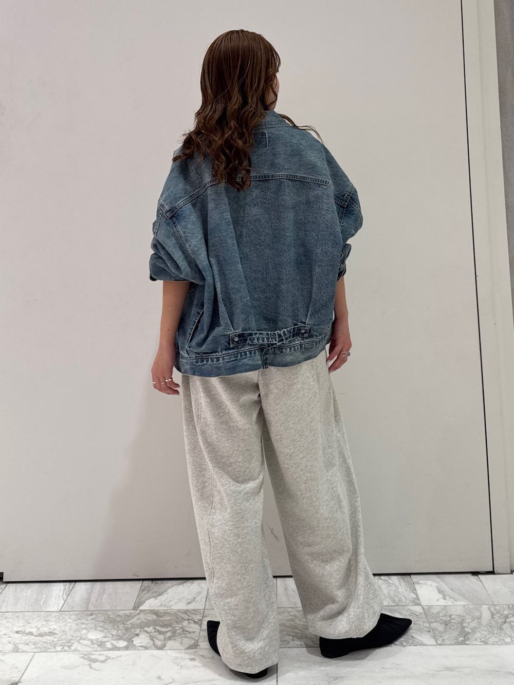 ブルー系のデニムジャケット、ブラック系のカーディガン/ボレロ、ホワイト系のスウェットパンツを着用したレディースの冬コーディネートの4枚目の写真