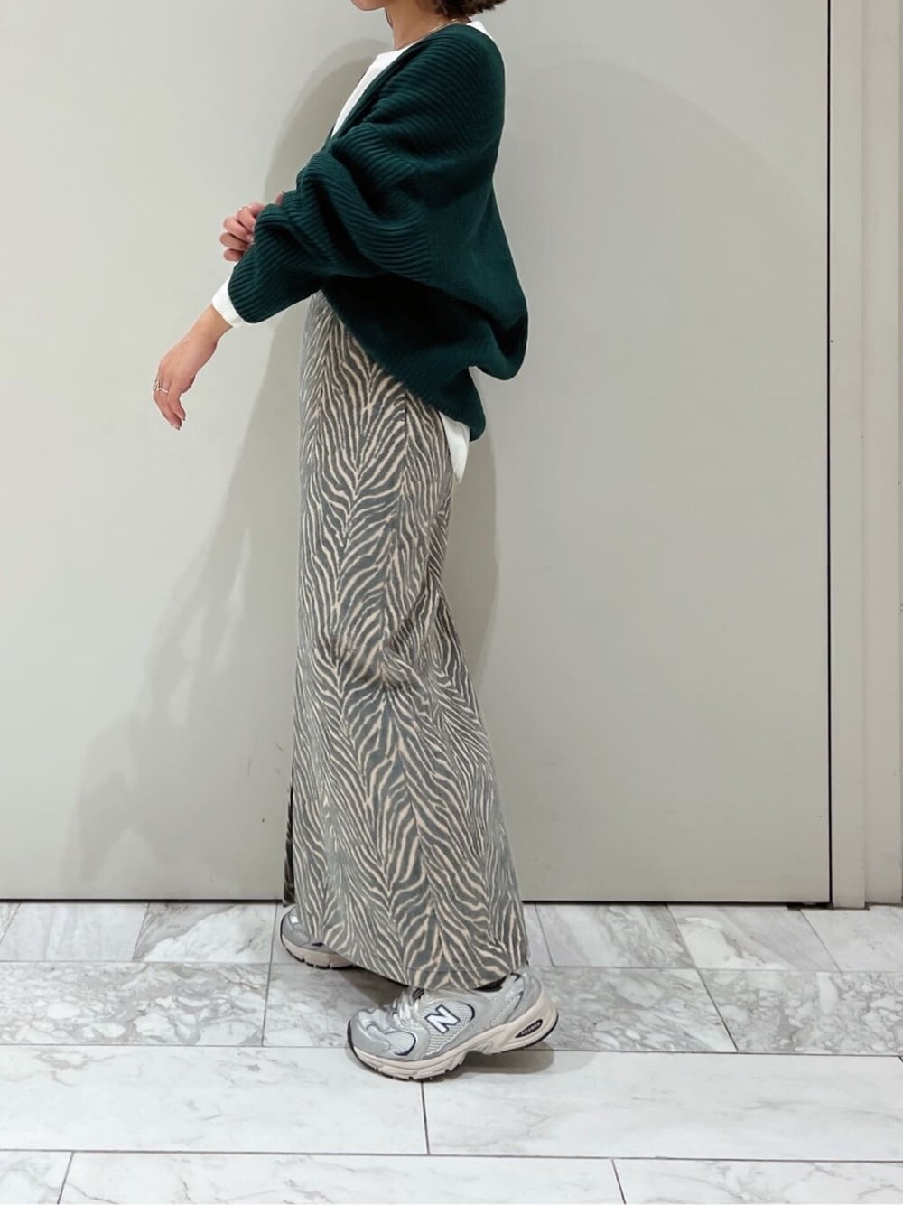 ホワイト系のTシャツ/カットソー、ブルー系のスカート、グリーン系のニット/セーターを着用したレディースの秋コーディネートの5枚目の写真