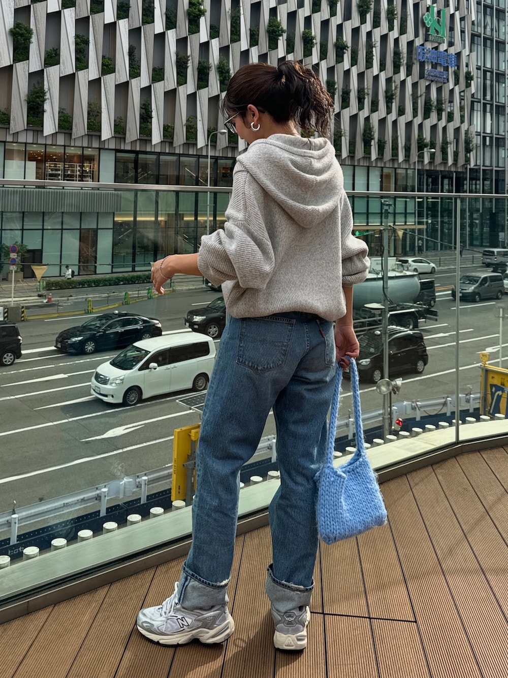 ブルー系のハンドバッグ、グレー系のニット/セーター、ブルー系のデニムパンツを着用したレディースの秋コーディネートの3枚目の写真