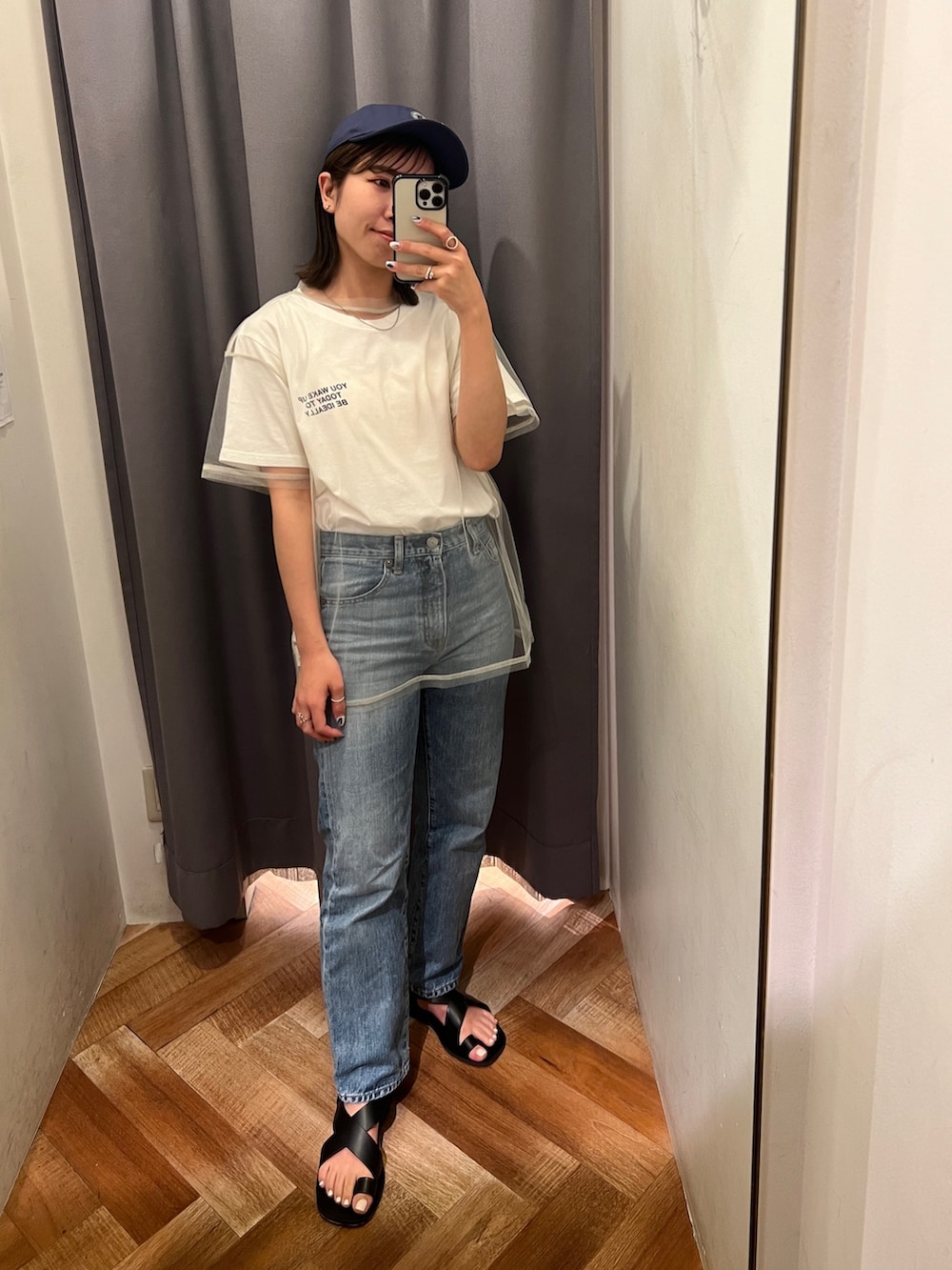 ブルー系のデニムパンツ、ブラック系のサンダル、ホワイト系のTシャツ/カットソーを着用したレディースの春コーディネートの3枚目の写真