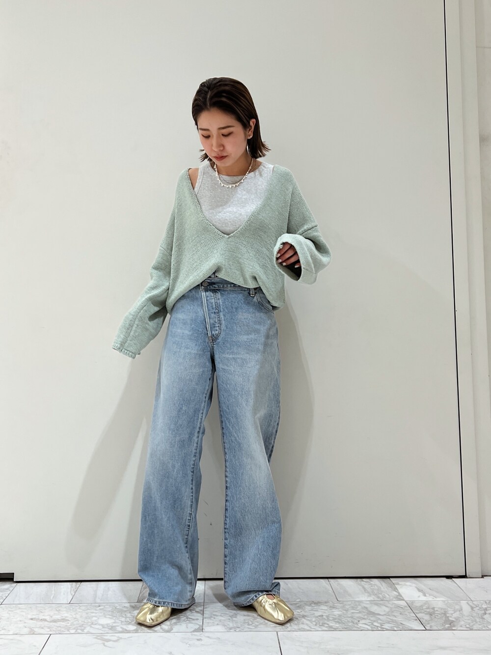 ブルー系のデニムパンツ、イエロー系のパンプス、グリーン系のニット/セーターを着用したレディースの冬コーディネートの5枚目の写真