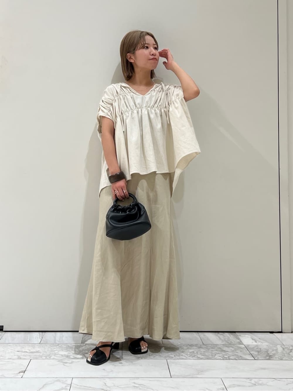 ブラック系のサンダル、ベージュ系のスカート、ホワイト系のシャツ/ブラウスを着用したレディースの夏コーディネートの3枚目の写真