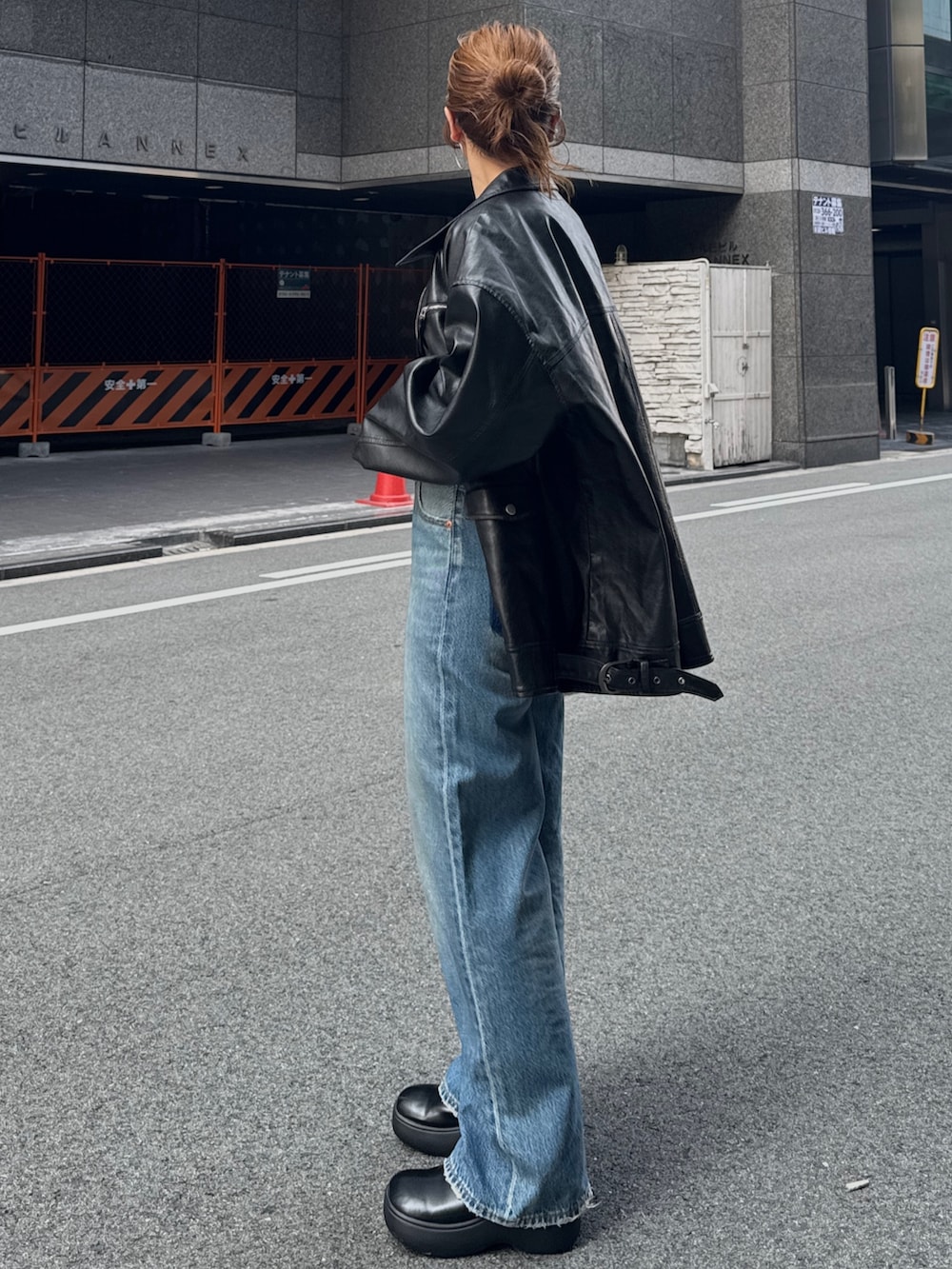 ブラック系のブルゾン、ブルー系のデニムパンツを着用したレディースの秋コーディネートの4枚目の写真