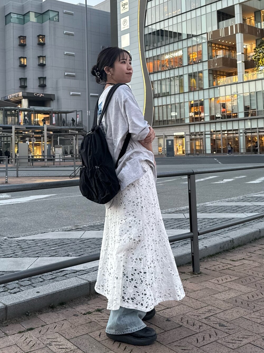 ブラック系のバックパック/リュック、ホワイト系のスカート、グレー系のTシャツ/カットソーを着用したレディースの冬コーディネートの2枚目の写真